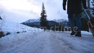 在冬天的白天，不可辨认的人在小径上行走，在车轮上拉着手提箱。 年轻人和他一起
